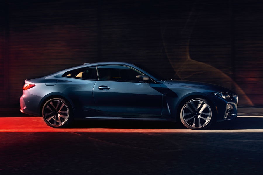 BMW 4 Series coupe displayed in a dimly lit room, highlighting its sleek design and elegant lines.